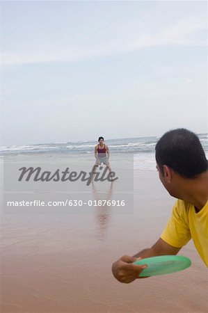 Two young men playing with a plastic disc on the beach