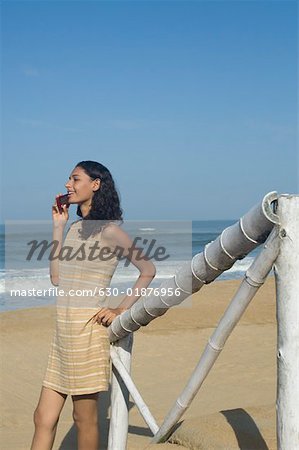 Seitenansicht einer jungen Frau im Gespräch auf dem Handy am Strand