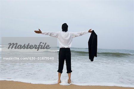Vue arrière d'un jeune homme debout sur la plage