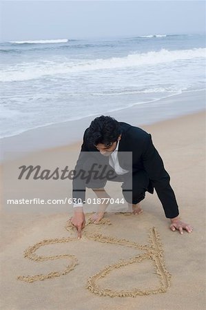 Businessman writing in sand on the beach