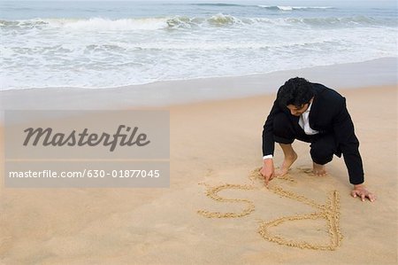 Young man drawing Rs on the beach