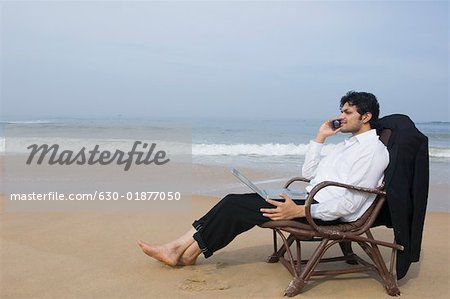 Side profile of a businessman sitting in an armchair and talking on a mobile phone