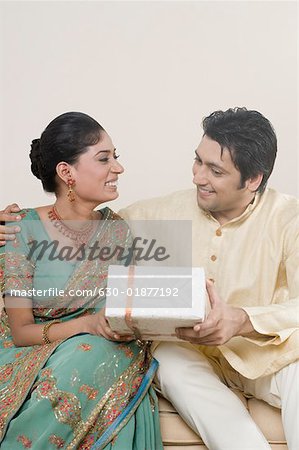 Mid adult man giving a gift to a young woman and sitting together