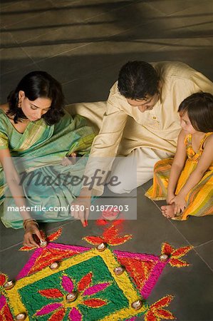 Vue d'angle élevé d'un homme adult moyen et une jeune femme faisant rangoli avec leur fille