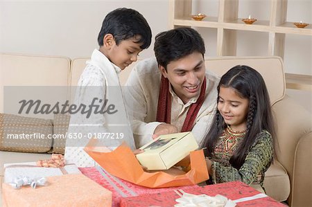 Young man opening a gift in front of his children