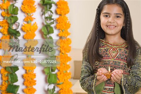 Portrait of a girl holding a diwali lamp and smiling