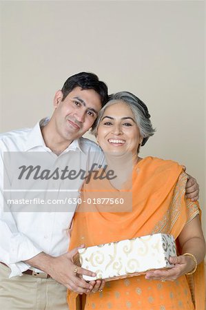 Portrait of a mature woman and her son holding a gift and smiling