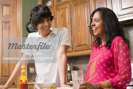 Mature woman smiling with her son in the kitchen
