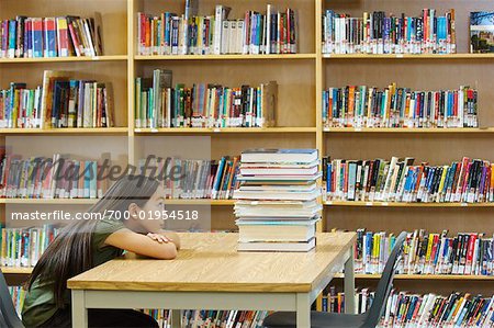 Studentin in der Bibliothek, Blick auf Stapel Bücher