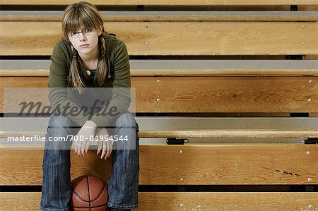 Étudiant avec Basketball assis dans les gradins du gymnase