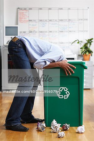 Homme cherchant dans le bac de recyclage