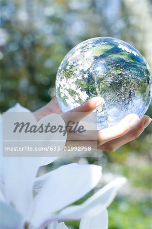 Woman holding glass sphere in hand, cropped view