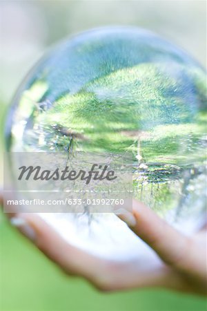 Woman holding glass ball in hand outdoors, extreme close-up