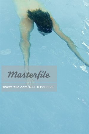 Man swimming underwater in pool, arms stretched in front of him