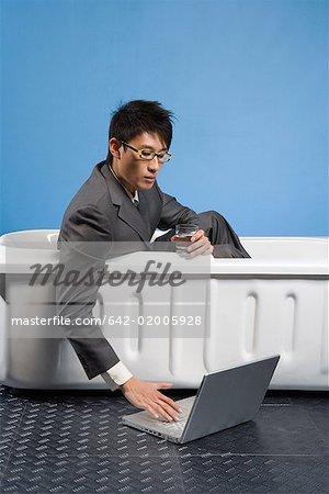 a business man sitting in the bath and seeing the lip-top