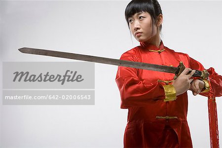 a woman in red dress practicing Chinese Kungfu with a sword