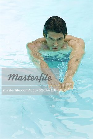 Man swimming in pool, arms out, high angle view