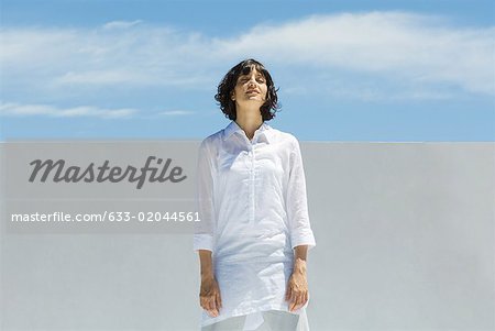 Woman standing outdoors with eyes closed, head back, smiling