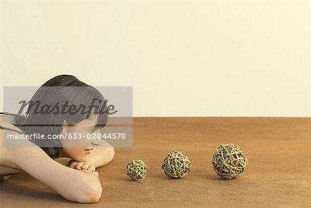 Woman resting head on arms, looking at balls of string, side view