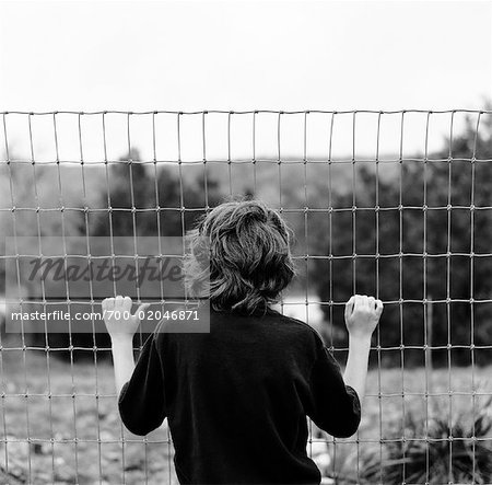 Boy Looking Through Fence