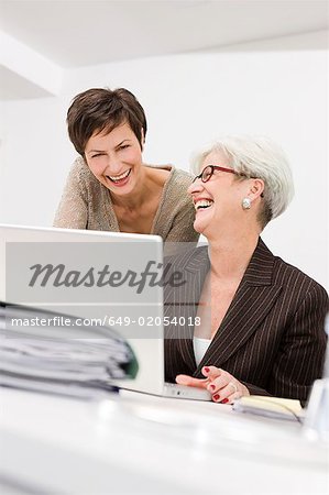 Zwei Frauen lachen vor einem pc