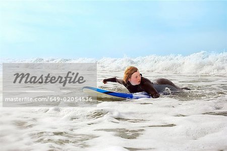 Femme couchée sur une planche de surf, pagayer