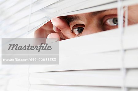 Homme regardant à travers les stores Bureau