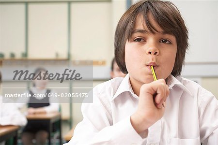 Boy with pencil in mouth, in classroom