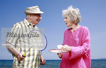 Senior couple on beach with badminton racquets and ball