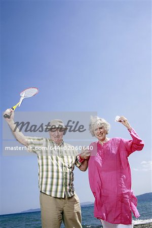 Senior couple on beach with badminton racquet and ball