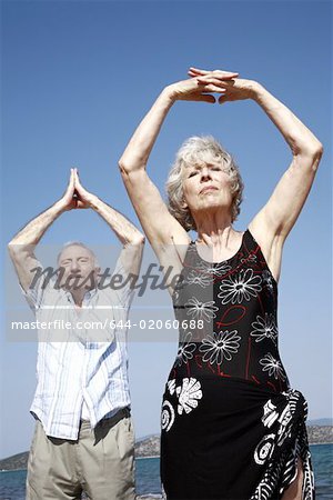 Senior couple stretching on beach