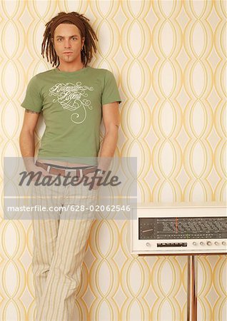 Young man with dreadlocks leaning against a wall