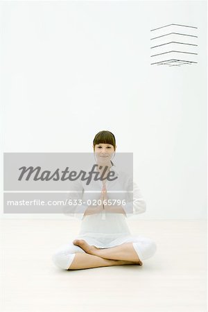 Woman sitting in lotus position on floor, smiling at camera