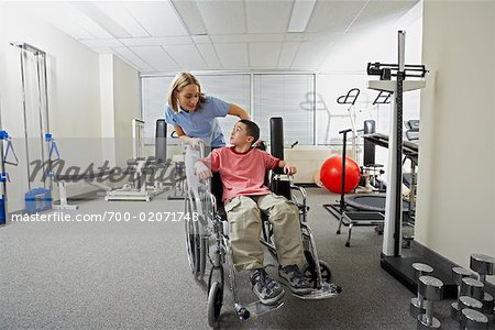 Physiotherapeut mit jungen im Rollstuhl