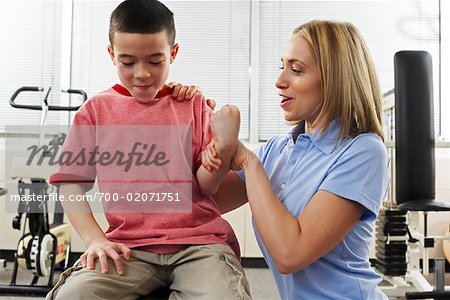 Phsiotherapist Testing Boy's Strength in Arm