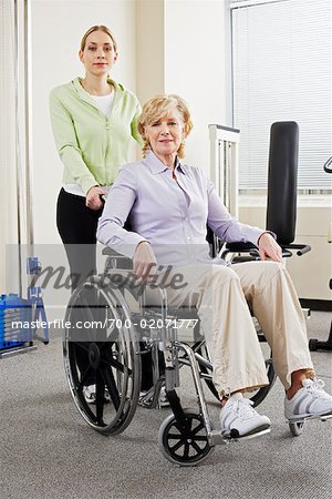 Physiotherapst mit Frau im Rollstuhl