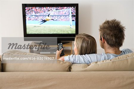 A young couple watching a football match on the tv