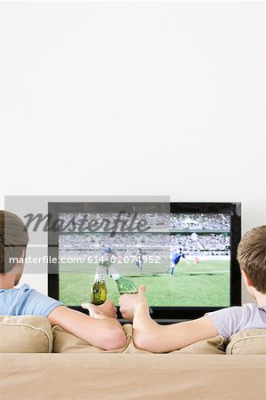 Deux jeunes hommes regarder le football sur la télévision