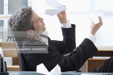 Homme d'affaires jouant avec des avions de papier au bureau