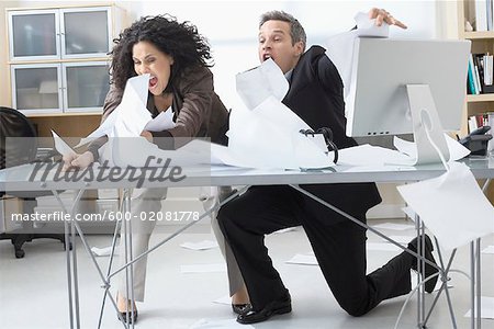 Business People Trying to Hold onto Paperwork Blowing Around on Desk