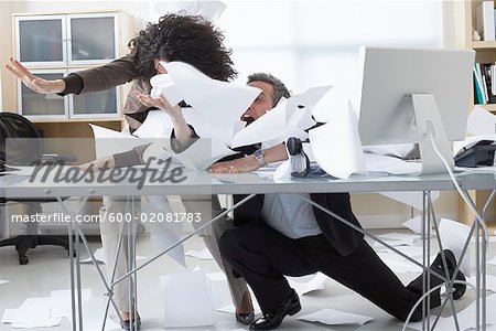 Business People Trying to Hold onto Paperwork Blowing Around on Desk
