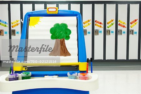 Easel with Child's Painting in Front of School Lockers