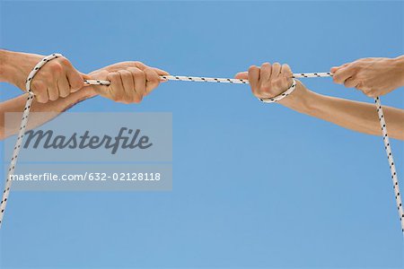 Hands playing tug-of-war with rope