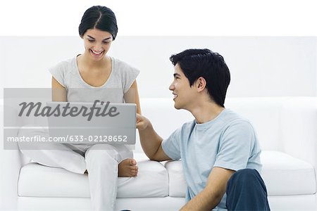 Woman sitting on couch using laZSop, man sitting on the ground, helping her