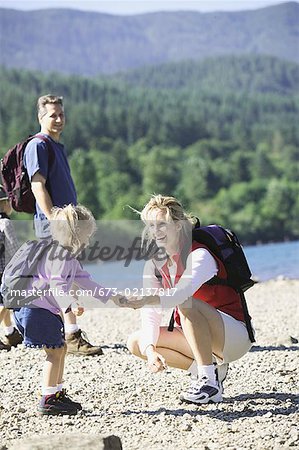 Mother helping young child on a hike.