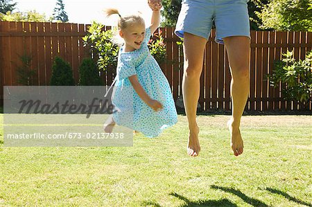 Young girl jumping with her mother.