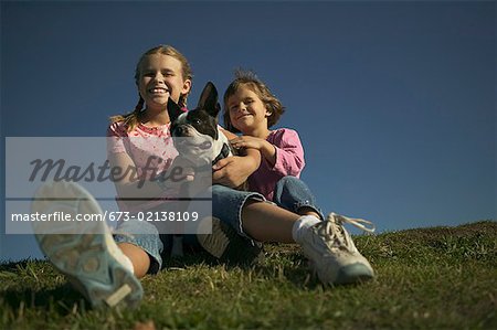 Deux jeunes avec leur chien de compagnie.