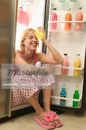 Femme assise dans un réfrigérateur ouvert.