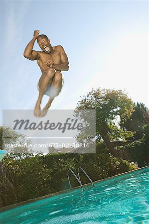 Homme sautant dans une piscine.