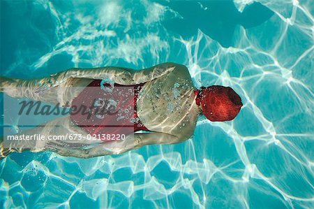 Obenliegende Ansicht einer Frau unter Wasser schwimmen.